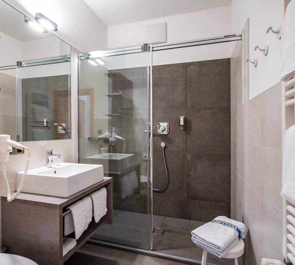 Modernes Badezimmer mit Glasdusche, Waschbecken und Handtüchern